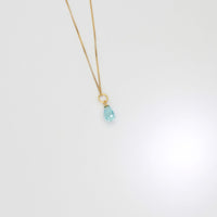 Gold necklace with a blue pendant on a white background