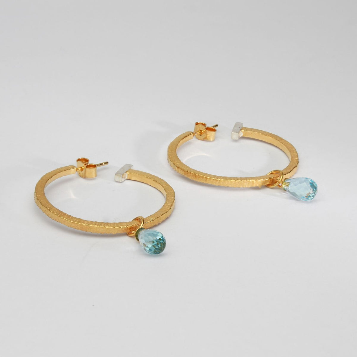 Textured hoops with blue topaz silver with 22ct gold plating by Charlotte Reid