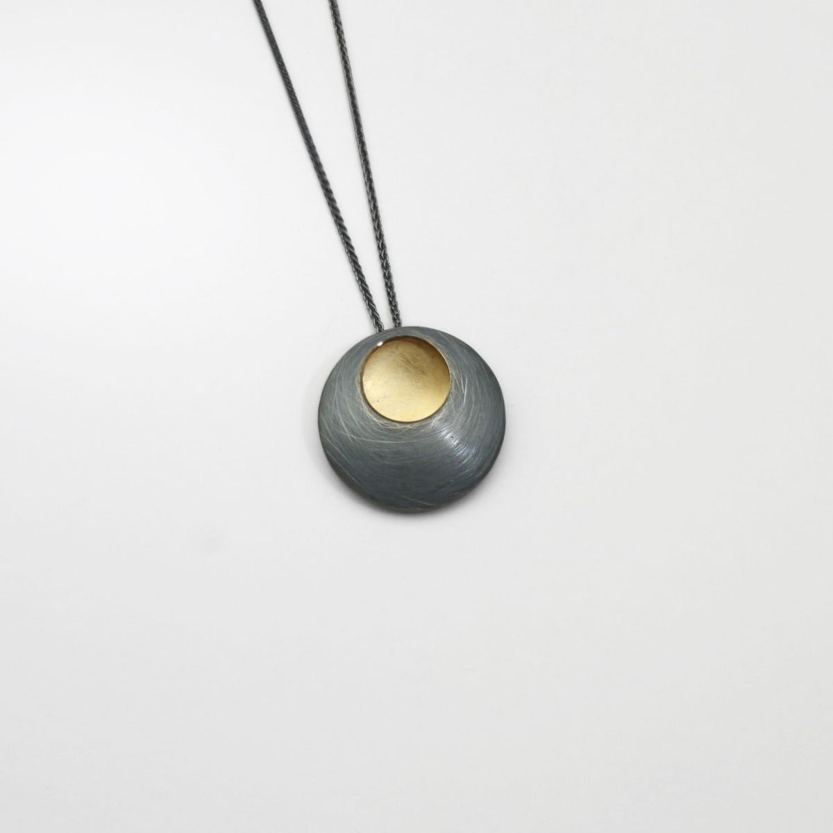 Large pebble black silver & gold plated pendant by Hannah Souter