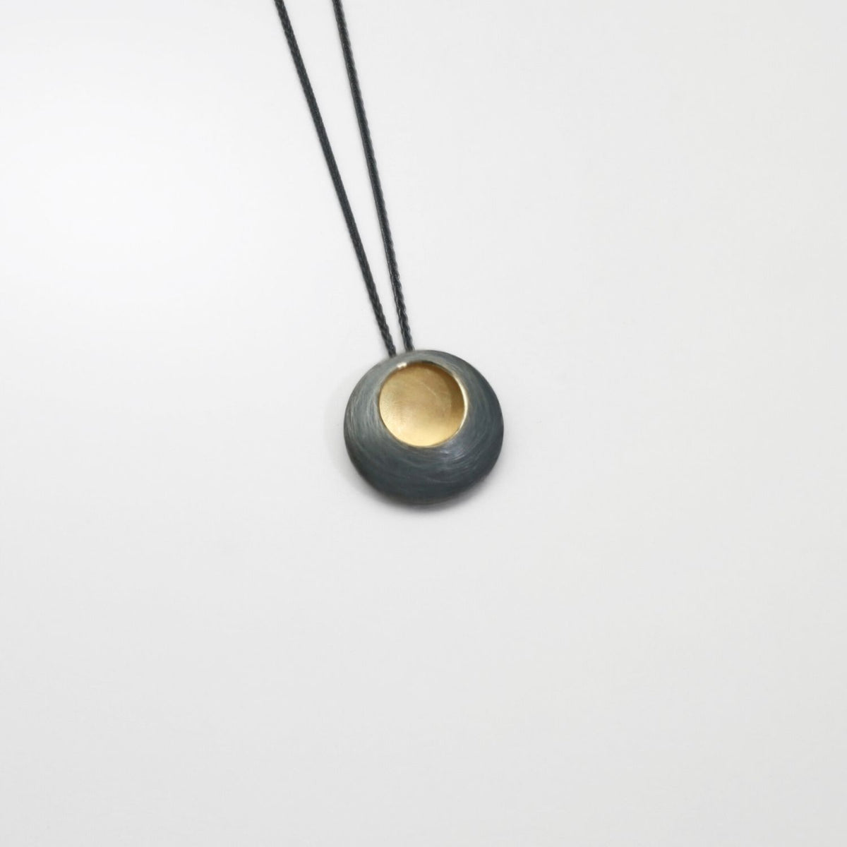 Small pebble black silver & gold plated pendant by Hannah Souter
