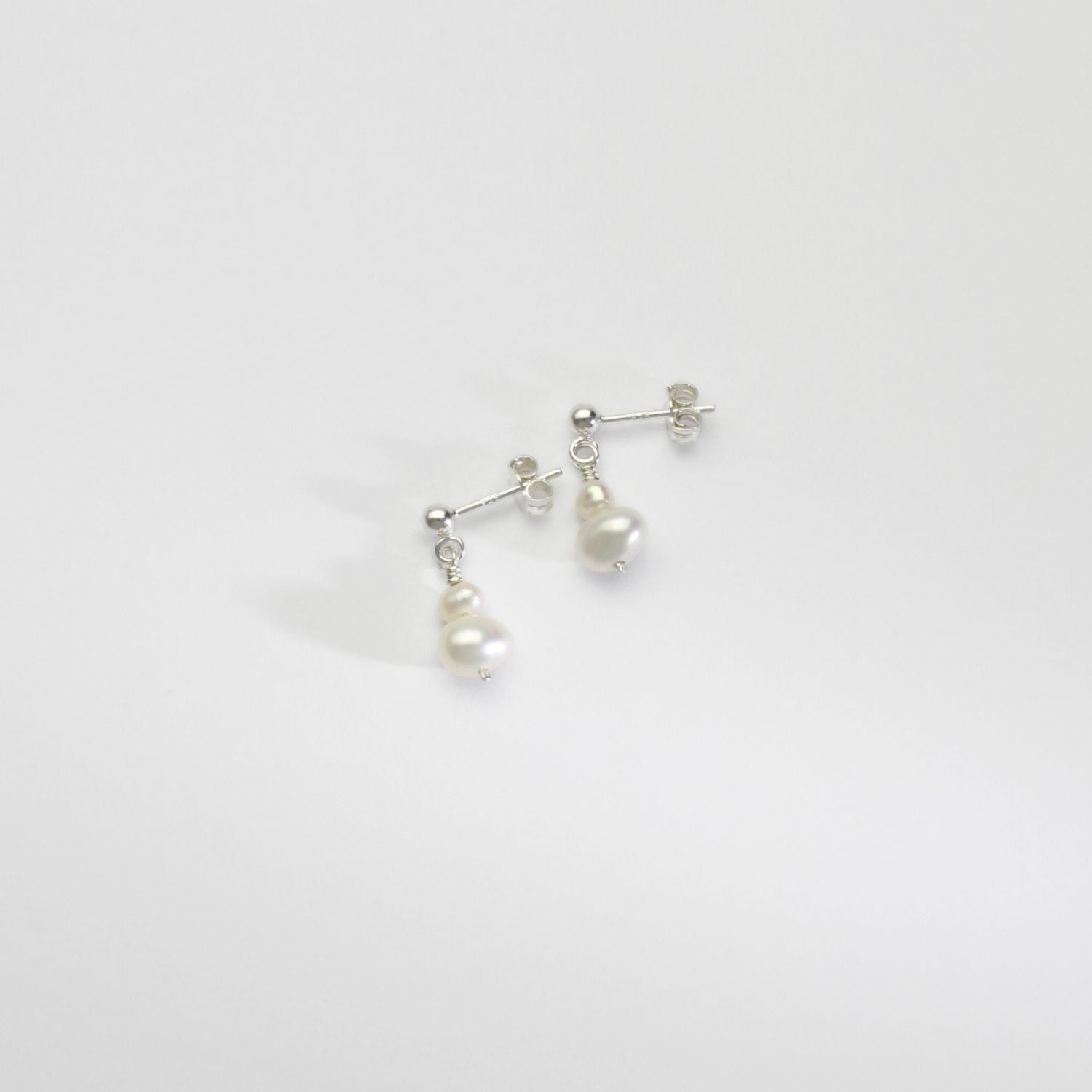 Small white squab & wee white pearl silver stud earrings by Natalie Vardey