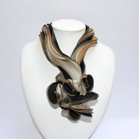 A black and gold silk scarf with textured details displayed on a mannequin bust