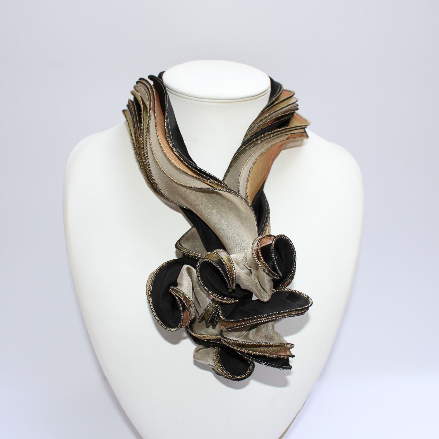 A black and gold silk scarf with textured details displayed on a mannequin bust