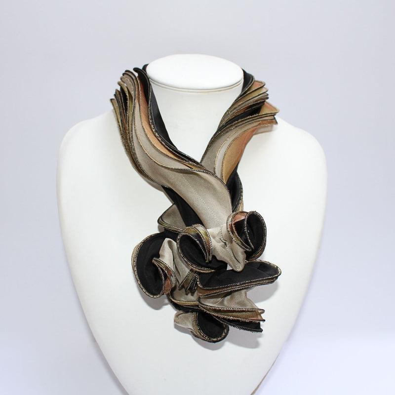 A black and gold silk scarf with textured details displayed on a mannequin bust