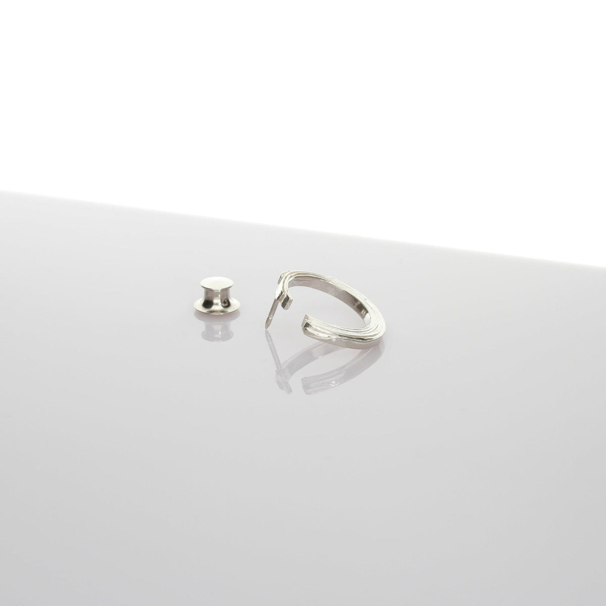 Close-up of the Brushstroke lapel pin's fluid line, echoing an artist's gesture