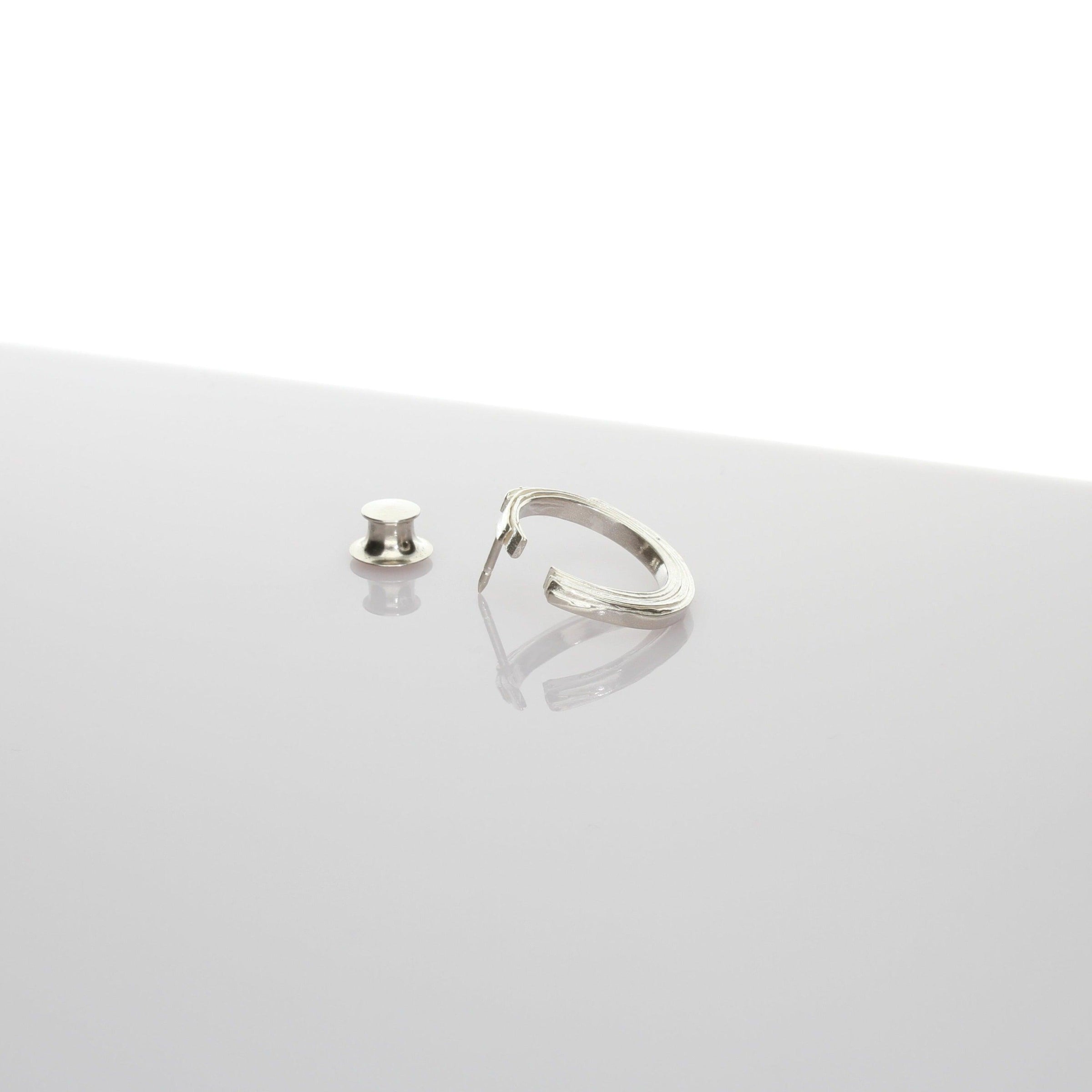 Close-up of the Brushstroke lapel pin's fluid line, echoing an artist's gesture