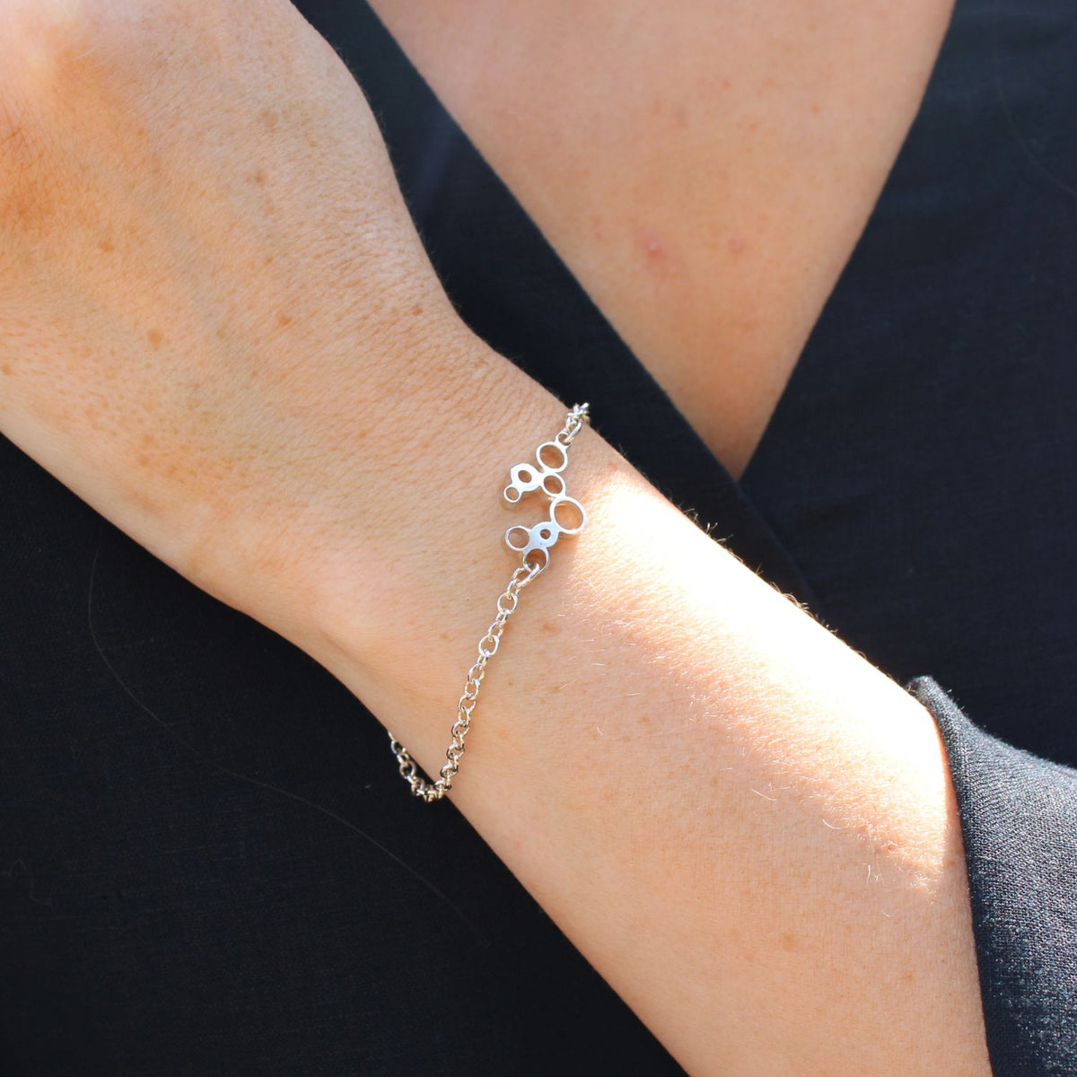 Model wearing the Bubbles charm bracelet, celebration-inspired design — Breichled Arian
