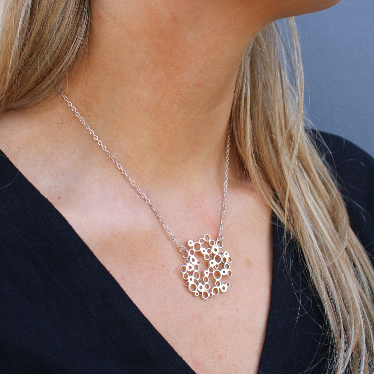 Model wearing the Bubbles medium pendant, celebration-inspired design — Mwclis Arian