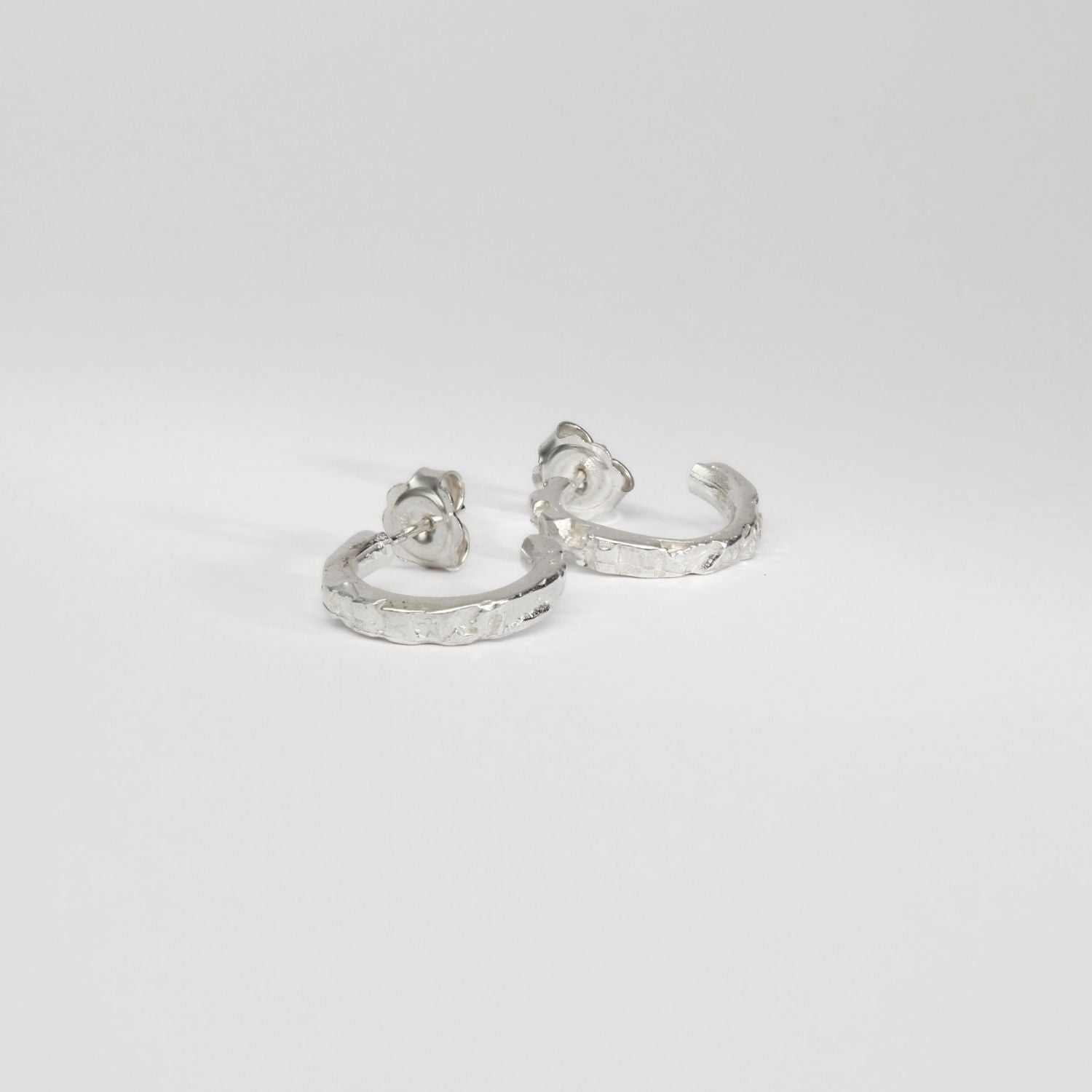 Carved sterling silver hoop earrings, side view showing texture
