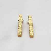 Close-up on the Cofio earrings, engraved with a line of Welsh poetry — Clustdlysau Arian ac Aur