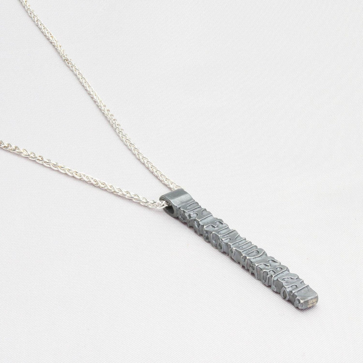 Close-up on the Cofio pendant, engraved with a line of Welsh poetry — Mwclis Arian