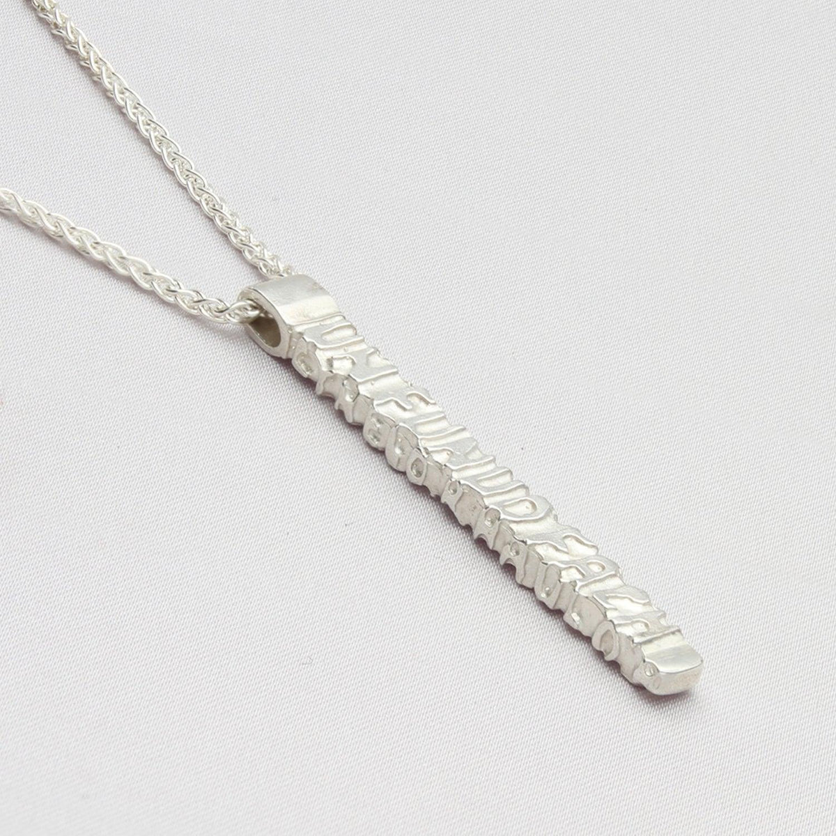 Close-up on the Cofio pendant, engraved with a line of Welsh poetry — Mwclis Arian