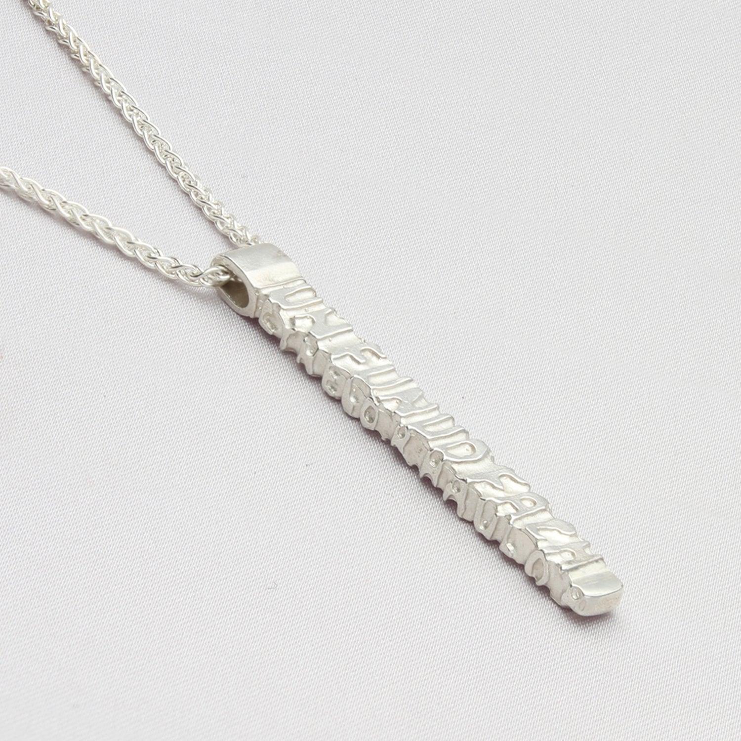 Close-up on the Cofio pendant, engraved with a line of Welsh poetry — Mwclis Arian