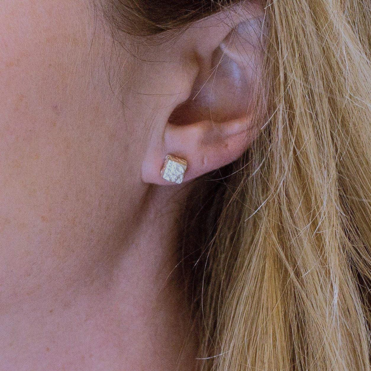 A pair of Cube studs, each carrying a piece of handwritten script — Clustdlysau Arian