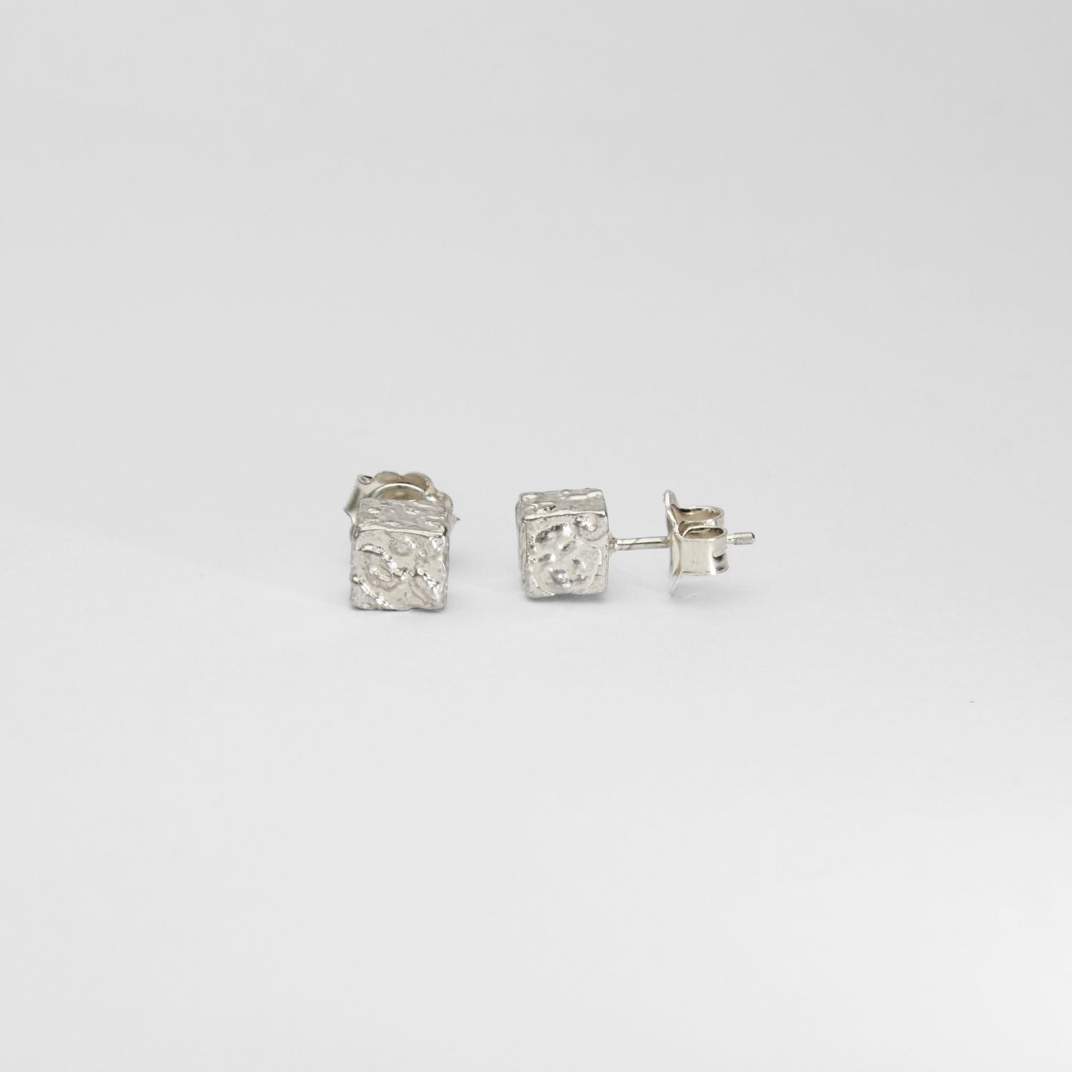 Side view of the Cube stud, tracing a fragment of writing — Clustdlysau Arian