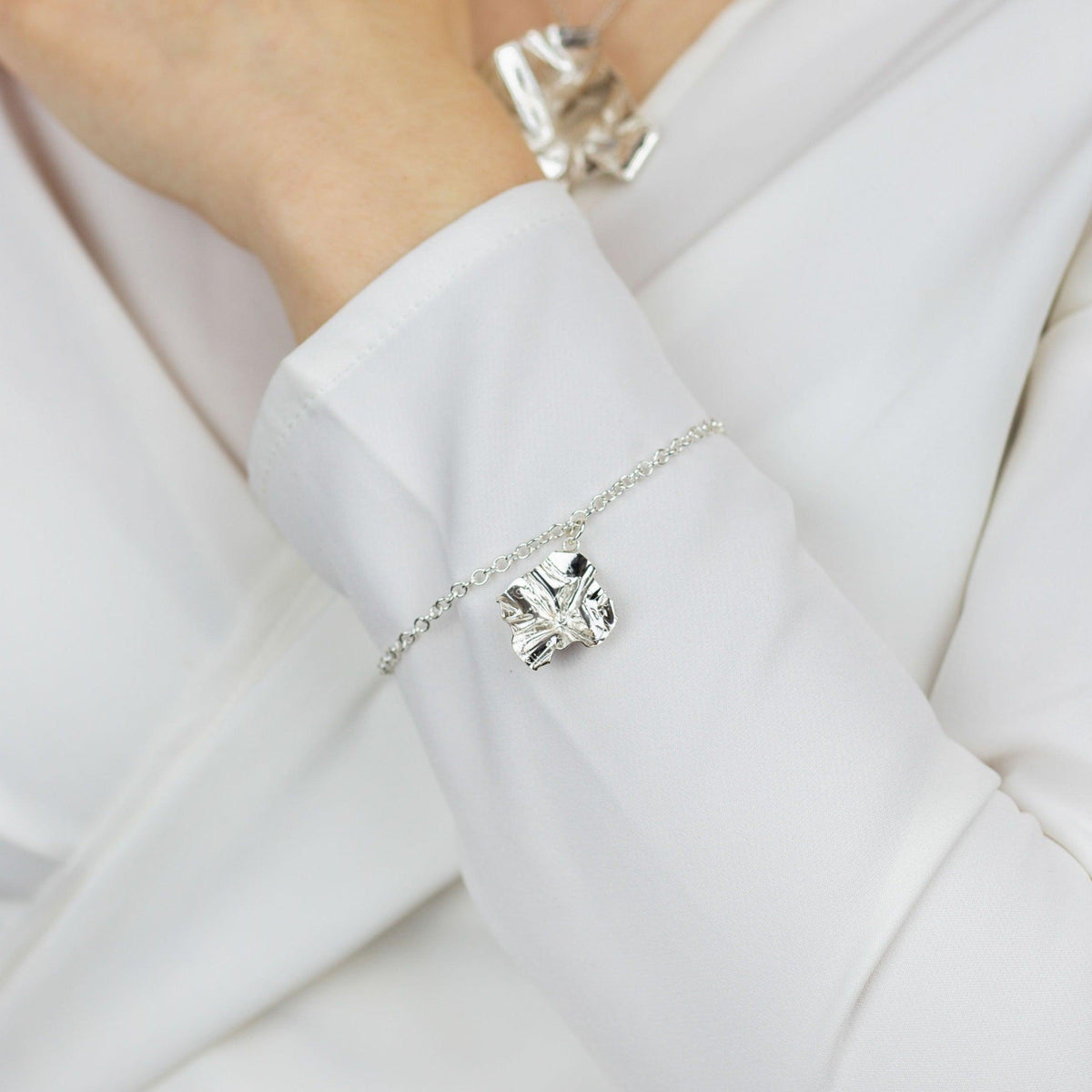 Close-up of the Decorative Concepts rose gold charm, echoing a writer's pencil line — Breichled Arian ac Aur