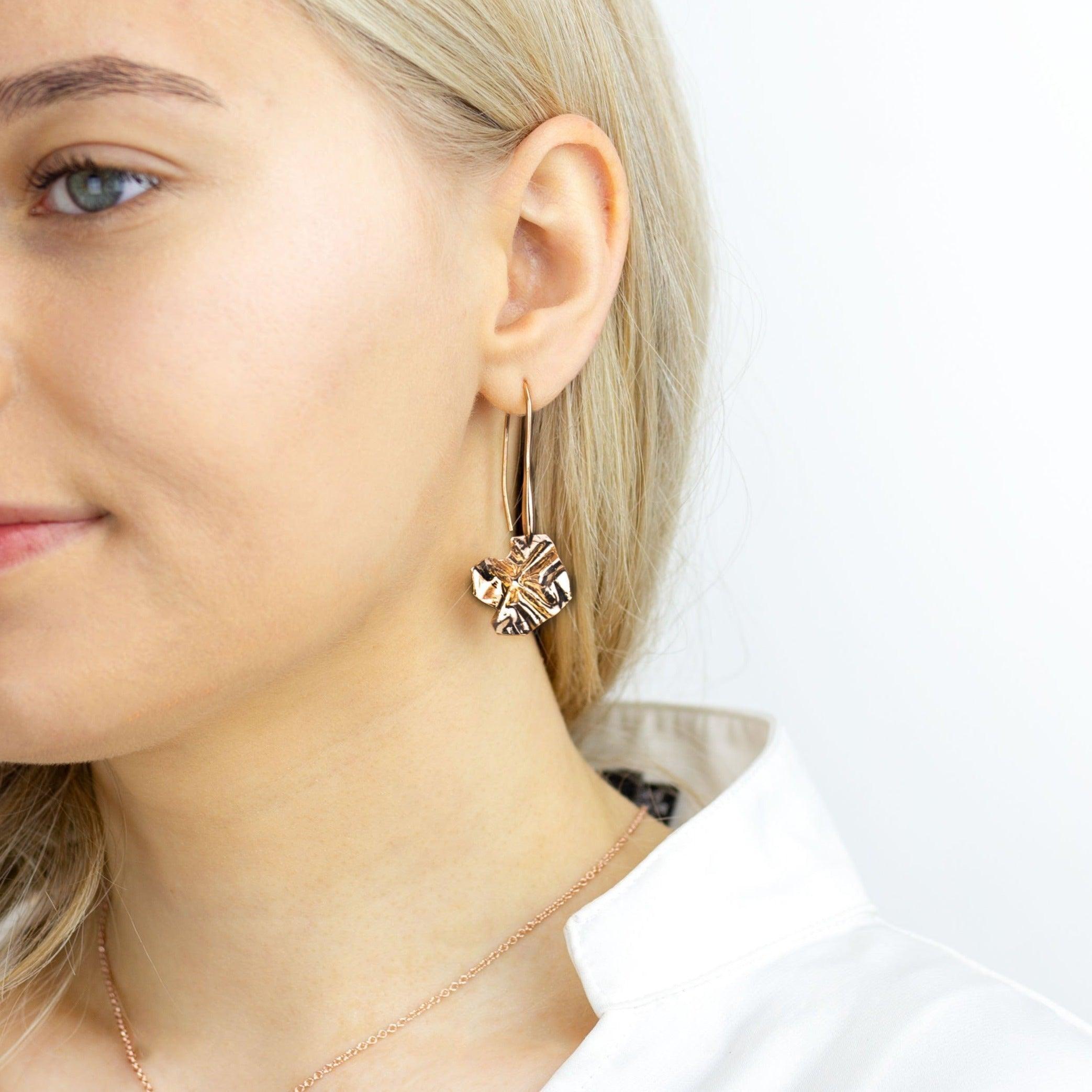 Side view of the Decorative Concepts rose gold drop earrings, an artist's pen stroke — Clustdlysau Arian ac Aur