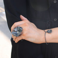 Model wearing the Decorative Concepts large ring and charm bracelet, echoing handwritten script — Modrwy Arian