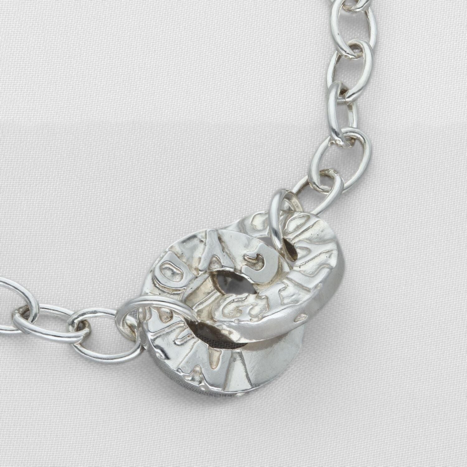 The Welsh word for togetherness, engraved by hand on a Gyda'n Gilydd charm — Breichled Arian
