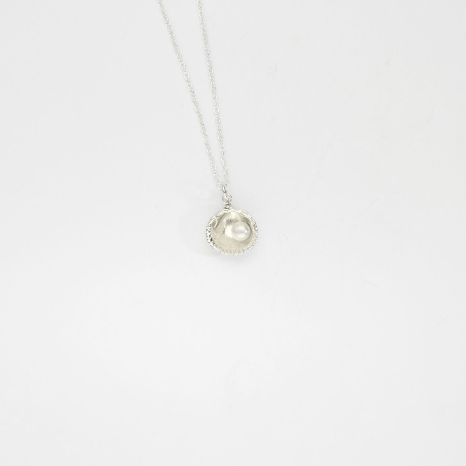 Small silver cockle pendant with cream freshwater pearl by Kate Wimbush